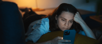 woman looking at her phone in bed at night