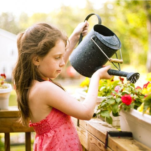 Girl-watering-flowers a young girl watering flowers