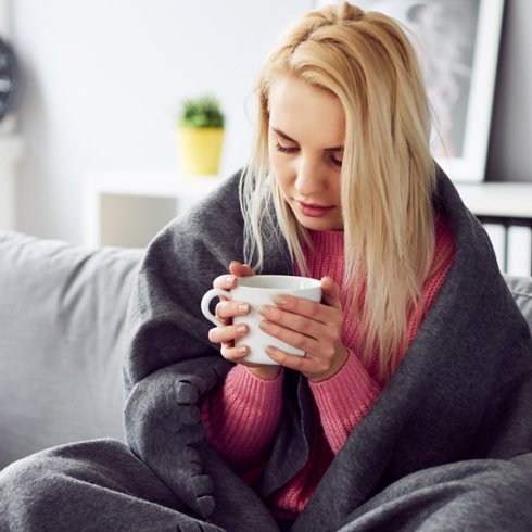 Woman on couch sick with blanket