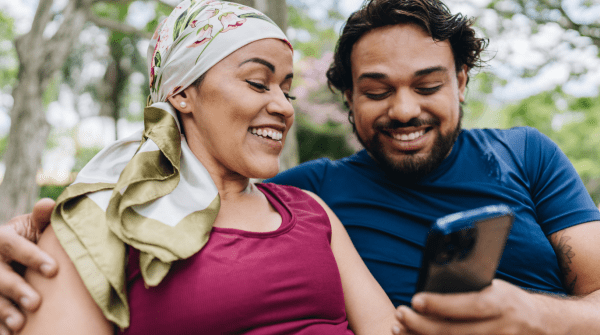 man and woman sit together outside using a phone