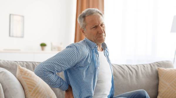 man sitting on couch experiencing lower back pain