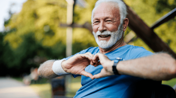 man sitting on a bench making a heart symbol with his hands