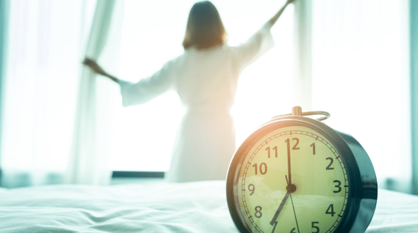 woman opening the curtains in her room with clock in the foreground