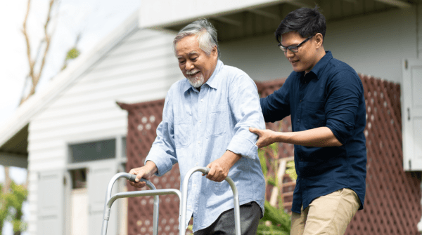 man acting as a caregiver to another man with a walker