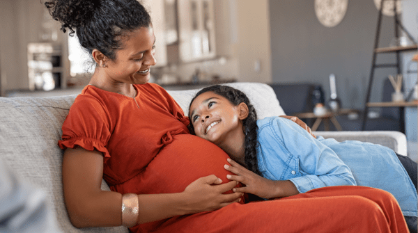 pregnant mom sitting on couch with daughter