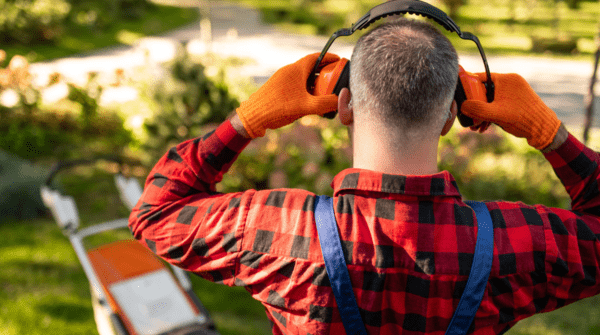 man putting on hearing protection before mowing lawn