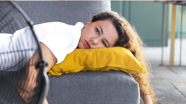 woman laying on the couch in front of a fan