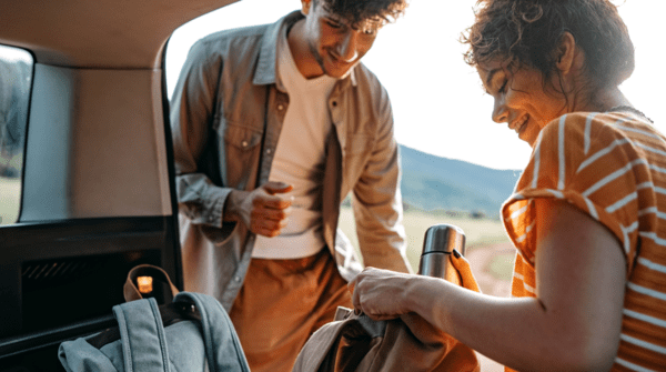 A couple packs their backpacks in the back of a car before a hike