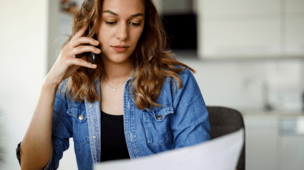 woman looking at a bill and laptop while on the phone