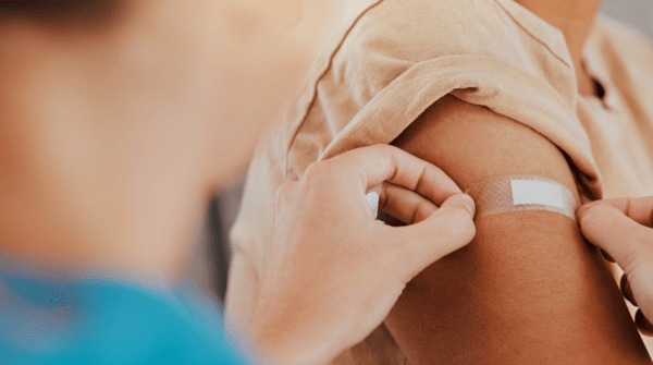 woman applying a bandaid to an arm after a vaccine