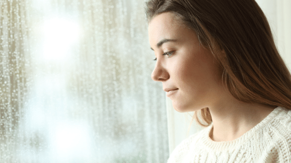 young woman looking out a window during winter