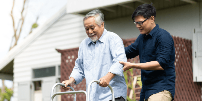 man acting as a caregiver to another man with a walker