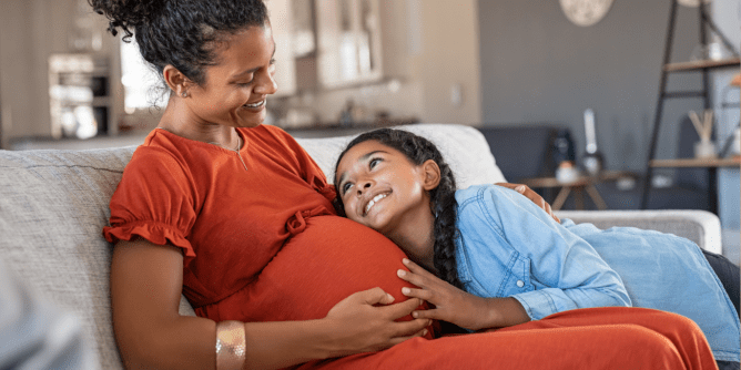 pregnant mom sitting on couch with daughter