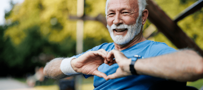 man sitting on a bench making a heart symbol with his hands