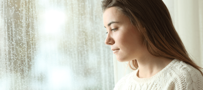 young woman looking out a window during winter
