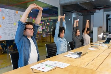 Employees stretching in office meeting for worksite wellness