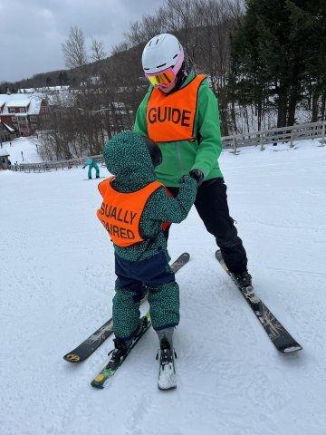 Visually impaired child skiing with guide